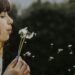 girl blowing on dandelion