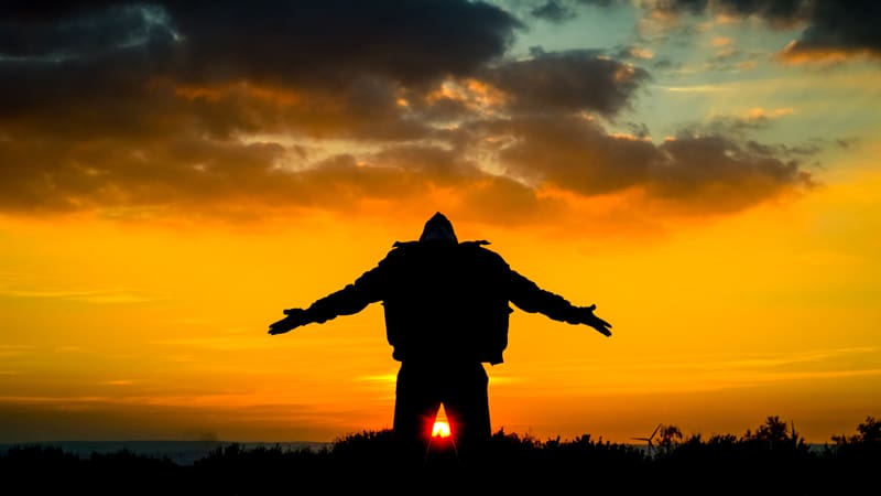 man raising his hands in the sunrise