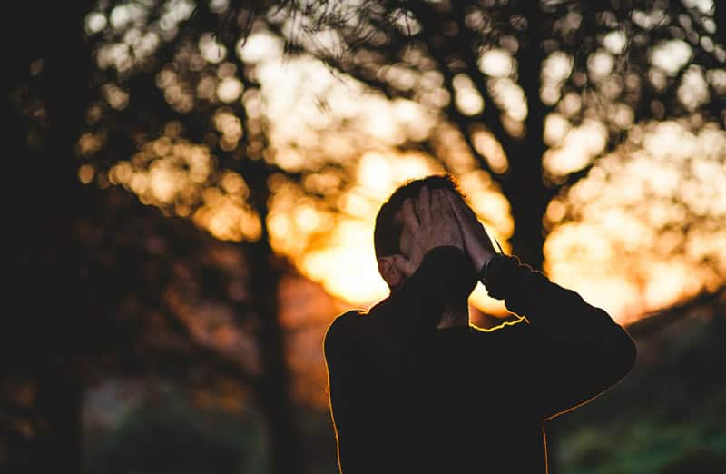 man covering his face with his hands
